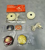 Overview of pillow speakers with wires and four tins of gramophone needles and ointment in plastic bags