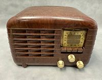 Front-right angled view showing the radio's Bakelite case with tuning dial and three knobs.