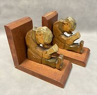 Pair of carved wooden bookends showing boy reading design, photographed from an angle showing details and wood tone.