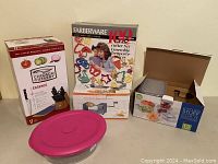 Full view of lot items including Chicago Cutlery knife set, Farberware cookie cutter set, glass and plastic storage containers, and boxed kitchen tools.