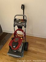 Full view of pressure washer unit showing frame, engine, hose and nozzle gun