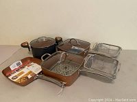 Full set arranged on table showing round pot, two square pots with baskets, glass lids, and wire baskets