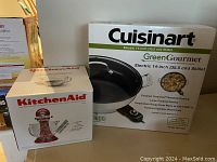 Photo showing boxed Cuisinart GreenGourmet electric skillet and boxed KitchenAid mixing bowl.