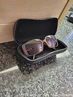 Chanel sunglasses in open black quilted case on dark countertop