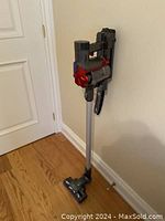 Full assembled vacuum with wand and motor head standing against wall