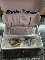 Eagle Eyes sunglasses inside white box with original plastic-wrapped hard case and informational booklet.