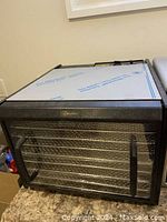 Front angled view of Excalibur dehydrator showing black frame, clear front door, and two black handles.