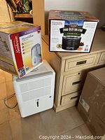Photo showing Whynter dehumidifier with control panel, Sunbeam humidifier box, and Jasmin food dehydrator box on wood cabinet.