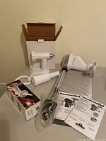 Wide view of food grinder and pasta maker attachments with manuals and box