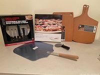 Photo of all items showing two pizza stones, two wooden pizza peels, pizza cutter, and wooden cutting board.
