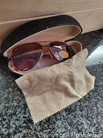 Serengeti sunglasses inside the open protective hard case with beige branded cleaning cloth in front.