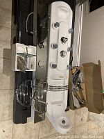Full view of the shower jet insert panel laid on the floor, showing multiple chrome jet controls, metal rail accessories, and the tap in its box.