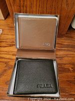 Tan Dolce & Gabbana wallet and black Prada wallet in their boxes displayed on wooden surface