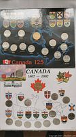 Front view of two Canadian commemorative coin sets, Canada 125 and Canada 1867-1992, displayed on cards with provincial shields and coins visible.