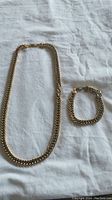 Full view of necklace and bracelet laid flat on white cloth
