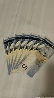 Seven Canadian $5 polymer bills fanned out, showing front side with Sir Wilfrid Laurier portrait.