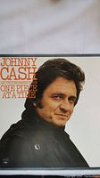 Front cover of Johnny Cash 'One Piece At A Time' LP featuring artist portrait and title text.