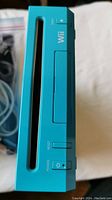 Front view of teal blue Nintendo Wii console showing disc slot, power, reset buttons and indicator lights.