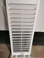 Close up of white slatted window shutter panel showing smooth finish and slats for light control.