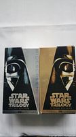 Front view of two Star Wars Trilogy Special Edition VHS boxes showing Darth Vader helmet design with silver and gold highlights.