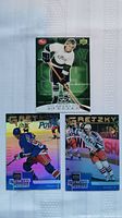 Front sides of three Wayne Gretzky hockey cards, one in white Kings jersey, two in blue Rangers jerseys.