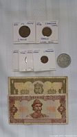Photo showing various coins and two banknotes including a 2 Drachmai Greece coin (1973), coins from 1949, 1950, 1975, 1980, and Ukrainian 1 and 2 Hryvnia banknotes.