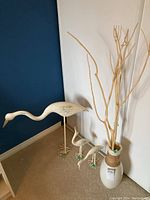 Photo showing the set of four metal bird sculptures and the vase with bleached wood branches against a blue and white wall.