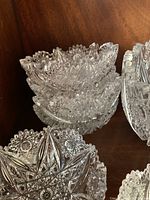 Clustered view of the six smaller crystal fruit nappies stacked and arranged, showing starburst cut designs and scalloped edges.