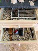 Second drawer containing various kitchen utensils such as rolling pin, peeler, tongs, and whisk, with patterned liner