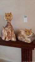 Both upright and reclining cat figures on a wooden shelf
