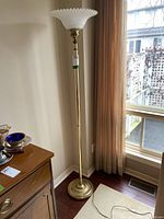Full view of vintage floor lamp with brass metal base and frosted glass shade near window and curtain