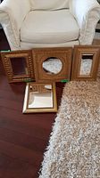 Four framed mirrors displayed on wooden floor beside a white upholstered chair and a cream carpet, showing relative sizes and frame detailing.