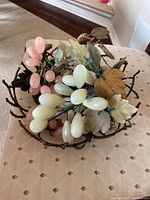 Top view of decorative semi-precious stone fruit clusters and leaves arranged inside the iron twig bowl.