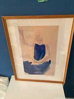Full view of the framed abstract print against a blue wall, showing the entire piece, frame and matting.