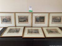 Seven framed prints arranged on a surface showing the scale and framing style, gold-tone frames, matting and glass protection.