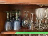 Shelf with blue iridescent goblets, clear glass decanter with stopper, and clear martini glasses.