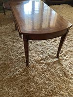 Side view of the rectangular wooden coffee table showing tapered legs and polished surface with scratches.