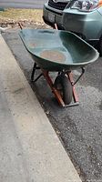 Side-angle view of the Yardworks wheelbarrow showing the green tray and orange frame.