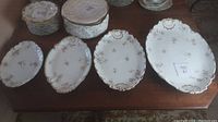 Four Limoges porcelain platters arranged by size showing floral pattern and gold trim on table.