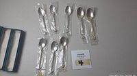All 8 unopened sterling silver spoons from Birks with original protective plastic packaging visible