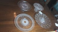 Wide shot of antique glass cake stand with two glass plates on dark wood table