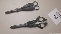 Two antique grape shears placed on a table, showing overall condition and design.