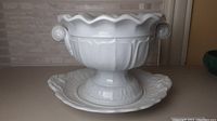 Side view of the white ironstone soup tureen on the matching base plate, showing scalloped rim and handles