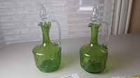 Photo of two matching green glass decanters with clear handles and stoppers, placed side by side