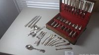 Overview of flatware on table and in open wooden chest