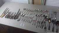 Full collection of mixed vintage and antique cutlery arranged on table.