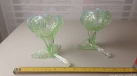 Two green clear floriform vases with textured petals and clear handle-like stems, placed next to a tape measure showing about 5 inches tall.
