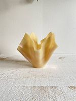 Front view of ruffled cream tan pearlescent glass vase with draped napkin style folds.