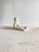 Left side angled view of the sandstone figurine showing the girl leaning backwards with textured dress details.