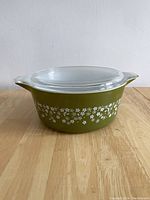 Side view of Pyrex casserole dish with lid, showing olive green color and white floral Spring Blossom pattern